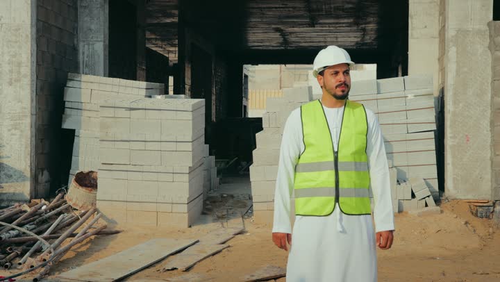 وظيفة ومهنة هندسية شبابية، مهندس عربي خليجي اماراتي يرتدي الكندورة والسترة وخوذة الحماية يعمل في القطاع الهندسي في الامارات العربية المتحدة، الاشرف على عمليات البناء، مفهوم ادارة المشاريع الهندسية والانشاءات، دراسة المخطط والمشروع على ارض الواقع