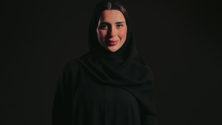 Using explanatory panels and educational tools, displaying advertisements and marketing offers, a white square mockup, and a photograph of a smiling Emirati Gulf Arab woman wearing a black abaya and hijab, holding a blank white square piece of paper in her hands, looking at the camera.