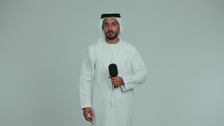 Working in radio and news broadcasting, a young Emirati Gulf Arab man wearing an Emirati kandura and ghutra giving a lecture and pointing at someone with his index finger, giving lectures and speeches and holding training workshops, educational professions and jobs, white background