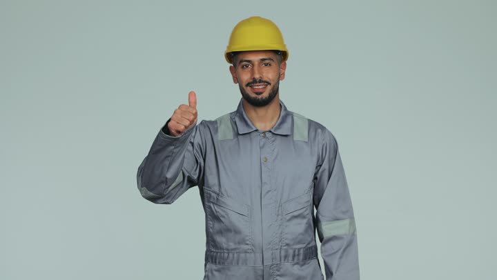 أعمال الإصلاح وورشات الصيانة في الإمارات العربية المتحدة, مهندس فني عربي خليجي اماراتي يرتدي الخوذة وبدلة السلامة يرفع اصبع الإبهام للتعبير عن الإعجاب والرضا، لباس رسمي للعمل في القطاع الهندسي، المهن والوظائف الشبابية، خلفية بيضاء