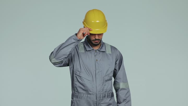 Formal dress for work in the engineering sector, repair and maintenance work in the United Arab Emirates, an Arab Gulf Emirati technical engineer wearing a helmet and safety suit standing with crossed hands and looking at the camera with gestures of happiness and pleasure, youth professions and jobs, white background
