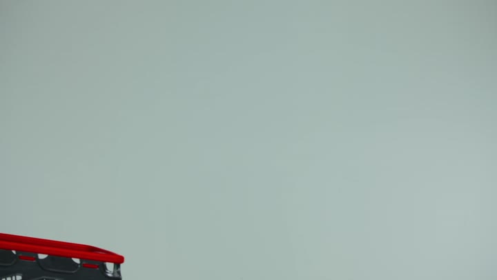 Having a good time shopping in the supermarket, taking advantage of discounts and offers on products, a side view of an Emirati Gulf Arab woman wearing a black abaya pulling a shopping cart to buy food, buying supplies and daily needs from the mall, white background
