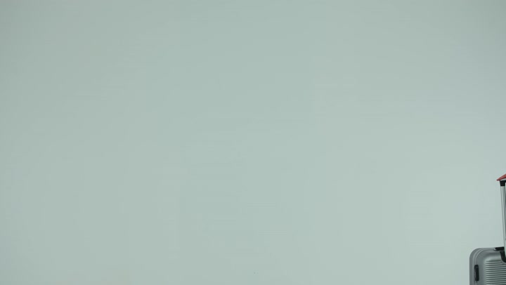 Summer vacation tourism, preparing to have a good time, preparing and getting ready for a fun trip, enjoying tourist trips during vacation time, side view of a veiled Emirati Gulf Arab woman wearing an abaya holding a gray suitcase, white background