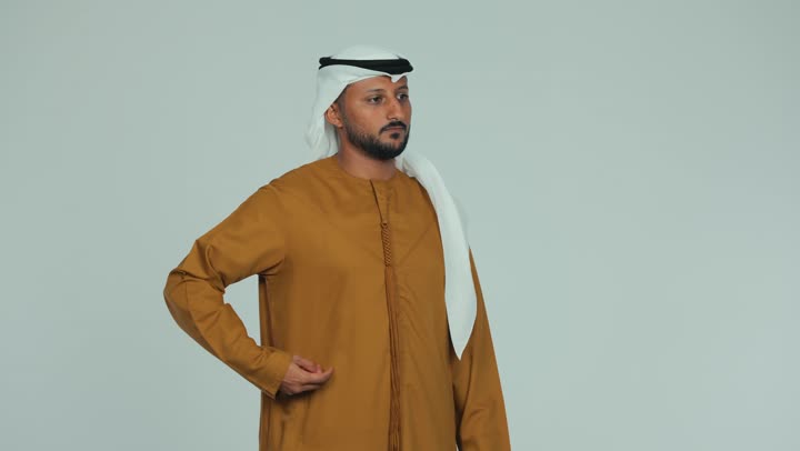 الاحتفاظ باللقطات التذكارية، التواصل مع الأهل والأصدقاء عبر الجوال، رجل عربي خليجي اماراتي يرتدي الكندورة والغترة يقوم بالتقاط صورة سيلفي بإيماءات السرور والسعادة، استخدام جهاز تقني حديث ومتطور، دردشة ومحادثة بين الرفاق، خلفية بيضاء