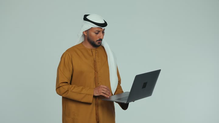 Gestures of direction and blame, managing and completing tasks using a modern technical device, close-up of an Emirati Gulf Arab man wearing a white kandura and ghutra conducting a business meeting via laptop, Emirati office jobs and professions, making a video call with family and friends, white background