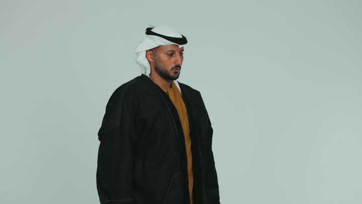 ارتداء الملابس الدافئة في فصل الشتاء، الأجواء الشتوية الباردة، الشعور بالصقيع والقشعريرة والتجمد، إيماءات وجه ويدين تدل على البرد الشديد، رجل عربي خليجي اماراتي يرتدي الفروة و والغترة يقوم تدفئة يديه، خلفية بيضاء