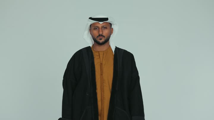 الإشارة بإصبع السبابة إلى شيء ما، مراقبة ومشاهدة الأشياء البعيدة، الرؤية المستقبلية وتحديد الأهداف والطموحات، رجل عربي خليجي اماراتي يرتدي الكندورة والغترة يمسك بيده  منظار ثنائي العينين وينظر من خلاله بإيماءات الذهول، خلفية بيضاء