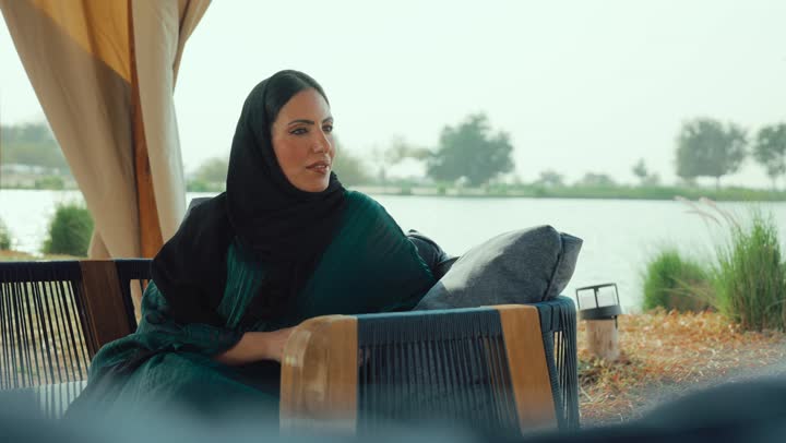 قضاء أوقات ممتعة ومسلية خارج المنزل, الشعور بالانتعاش والفرح، احتساء المشروب المفضل، تصوير لامراة عربية خليجية اماراتية محجبة ترتدي العباءة تجلس على الأريكة في إحدى المقاهي الراقية تحمل كوب من القهوه ، سيده سعودية تستمع بلحظات الهدوء والراحة