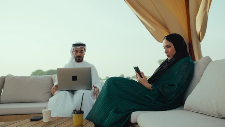 تطوير الاعمال والاستراتيجيات, النجاح وتحقيق الاهداف، رجل عربي خليجي اماراتي في اجتماع عمل ، استخدم جهاز الحاسوب المحمول ، تصوير مقرب لرجل عربي خليجي اماراتي يجلس مع امرأه في المقهى ، انجاز المشاريع والمهام في الكافيه.