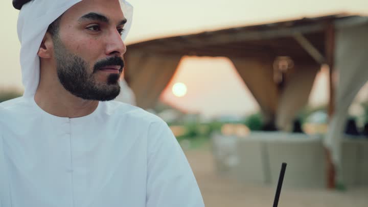 التسامر والدردشة وقضاء وقت ممتع مع الأصدقاء، تعابير السعادة والسرور بلمة الرفاق، كوفي شوب راقي بالامارات، تصوير مقرب لرجل عربي خليجي اماراتي يجلس في المقهى .