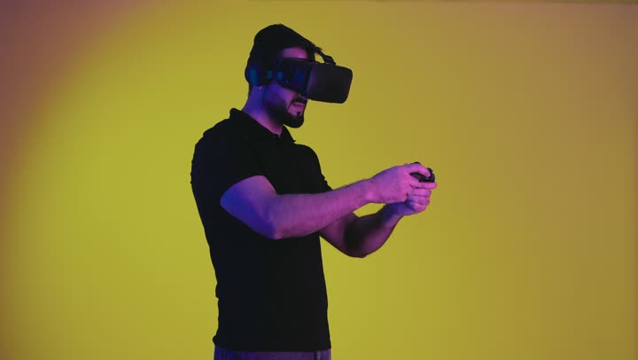 Playing video games, combining the fantasy world with fun and entertainment, portrait of an Emirati Gulf Arab man wearing casual clothes and virtual reality glasses holding a joystick, a Saudi young man feeling enjoyment and integration with modern devices, yellow background