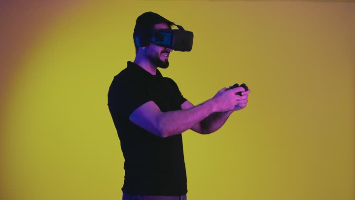 Playing video games, combining the fantasy world with fun and entertainment, portrait of an Emirati Gulf Arab man wearing casual clothes and virtual reality glasses holding a joystick, a Saudi young man feeling enjoyment and integration with modern devices, yellow background
