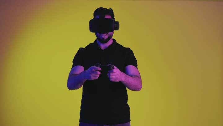 Gestures of integration and interaction, having fun with entertainment video games, portrait of a young Saudi Arabian Gulf man wearing casual clothes holding a controller, fun and entertainment with video games, a harmonious Emirati man wearing virtual reality glasses, yellow background