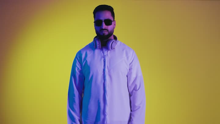 Giving time to do something, being quiet and asking to wait, a picture of an Emirati Gulf Arab man wearing the Emirati kandura and making gestures of patience, deliberation and deliberation, hand movement and signs, yellow background.