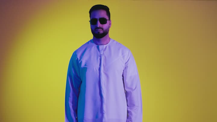 Expressing admiration and appreciation, excellence and full marks, raising a hand with signs of quality and acceptance, feeling satisfied and appreciative. A photograph of an Emirati Gulf Arab man wearing a kandura looking at the camera with gestures of happiness and pleasure, against a yellow background.