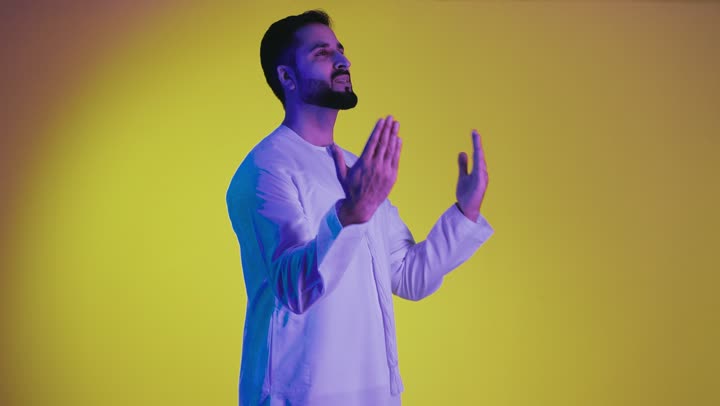 Simulating a fantasy world, the concept of elegance and attention to external appearance, containing and holding an element, a depiction of an Emirati Gulf Arab man wearing a kandura opening his hands to display three-dimensional holographic elements, yellow background.