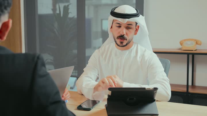 حوار ونقاش لتحقيق الاستراتيجيات والغايات, التفاهم والتعاون بين الزملاء لتحقيق أهداف الشركة, بيئة العمل المريحة في الشركات الإماراتية, استخدام الأجهزة التقنية الحديثة في المكاتب, اجتماع عمل بين موظفين عرب خليجيين اماراتيين في غرفة الاجتماعات، توقيع عقد وصفقة جديدة