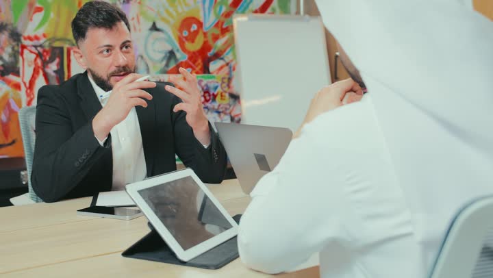 استخدام الأجهزة التقنية الحديثة في المكاتب, حوار ونقاش لتحقيق الاستراتيجيات والغايات, التفاهم والتعاون بين الزملاء لتحقيق أهداف الشركة, بيئة العمل المريحة في الشركات الإماراتية, اجتماع عمل بين موظفين عرب خليجيين اماراتيين في غرفة الاجتماعات