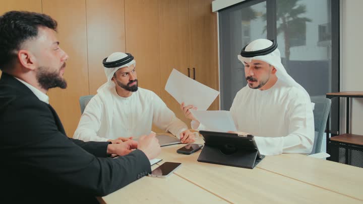 دراسة أوراق البيانات والنتائج، استخدام الأجهزة التقنية الحديثة في المكاتب, حوار ونقاش لتحقيق الاستراتيجيات, التفاهم والتعاون بين الزملاء لتحقيق أهداف الشركة, بيئة العمل المريحة في الشركات الإماراتية, اجتماع عمل بين موظفين عرب خليجيين اماراتيين في غرفة الاجتماعات