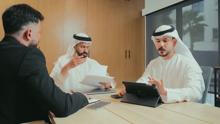 دراسة أوراق البيانات والنتائج، استخدام الأجهزة التقنية الحديثة في المكاتب, حوار ونقاش لتحقيق الاستراتيجيات, التفاهم والتعاون بين الزملاء لتحقيق أهداف الشركة, بيئة العمل المريحة في الشركات الإماراتية, اجتماع عمل بين موظفين عرب خليجيين اماراتيين في غرفة الاجتماعات