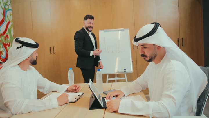 تحليل البيانات الاحصائية، دمج العمل مع التقنية الحديقة، مفهوم الإدارة المتعاونة، وضع الخطط الاستراتيجية لتحقيق الأهداف، استخدام السبورة لتوضيح الأفكار، مجموعة من الموظفين العرب الخليجيين الاماراتيين يعقدون اجتماع داخل مقر الشركة، تعلم اساليب العمل والتطوير المهني