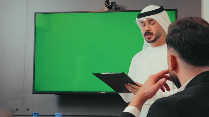 إدارة و تقسيم المهام، رجل عربي خليجي إماراتي يقوم بشرح المشروع داخل غرفة الاجتماعات للموظفين، فريق عمل يقوم بإجراء اجتماع لتبادل الخبرة وتطوير المشاريع و الاستثمارات، عرض شاشة كروما خضراء فارغة, دمج الأجهزة التقنية الحديثة بالأعمال لسهولة توصيل المعلومة