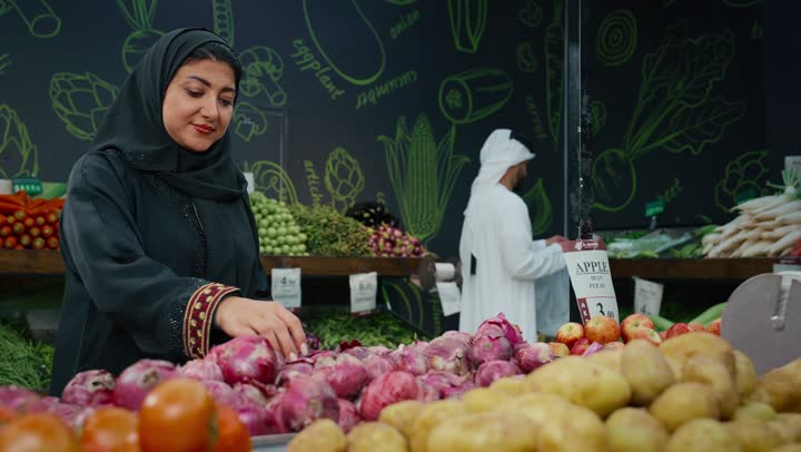 Meeting household needs, close-up of an Emirati Gulf Arab woman selecting fresh onions, a Saudi woman wearing a black abaya buying household needs, goods and various food items, consumer supplies, Saudi agricultural crops