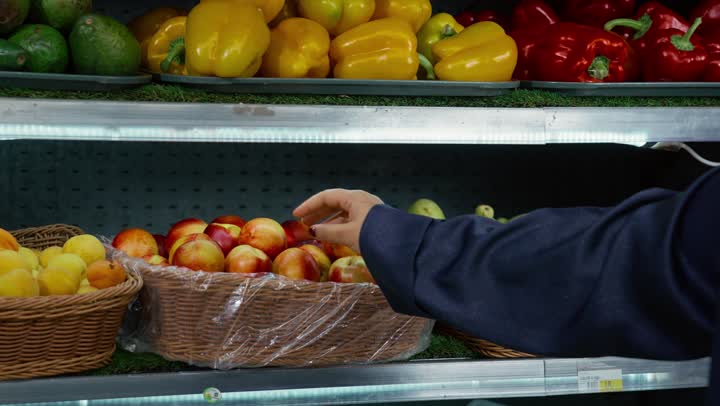 Ease and comfort in shopping, spending a pleasant time shopping and choosing household supplies, having different purchasing and consumption options from the supermarket, a veiled Arab Gulf Emirati woman wearing a gray abaya walking in one of the market sections and pulling a shopping cart, local national products