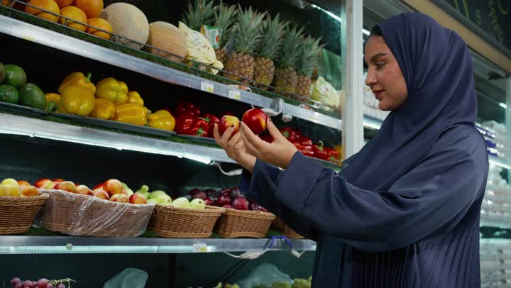 السهولة والراحة في التسوق, قضاء وقت ممتع في التبضع واختيار اللوازم المنزليه, امتلاك خيارات شراء و استهلاك مختلفة من السوبر ماركت، سيدة عربيه خليجية اماراتيه محجبة ترتدي عباءه رماديه تمشي في أحد أقسام الماركت وتقوم بجرعربة التسوق، منتجات محليه وطنيه