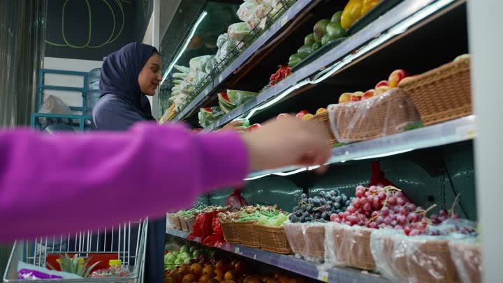 أم عربية خليجيه اماراتيه برفقة طفلتها في السوبرماركت، سيده سعوديه ترتدي عباءه رماديه تقوم بالتبضع وشراء ثمره الافوكادو، قضاء وقت ممتع في التسوق، عربة التسوق ، السلع والمواد الغذائية ، شراء الاحتياجات المنزلية، منتج محلي وطني