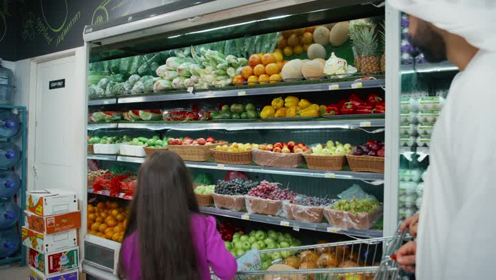 Shopping with the family in the supermarket, an Arab Gulf Emirati family shopping for everything their daughter loves in one of the mall sections, cooperation and consultation in purchasing household supplies and needs, choosing household goods and supplies, a local Emirati national product