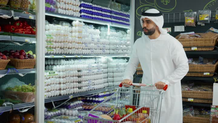 قسم الخضروات والفاكهه الطازجه، رجل عربي خليجي اماراتي يرتدي الكندوره والغتره يقوم بفحص حبات الفلفل الاصفراثناء التبضع والشراء، الاحتياجات المنزلية، السلع والمواد الغذائية، اختيار الفاكهه بجوده جيده، منتج محلي اماراتي
