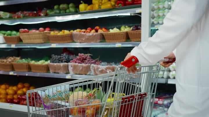 التبضع والتسوق في السوبر ماركت, قضاء وقت ممتع في التبضع واختيار اللوازم المنزليه, عربه تسوق مليئه بالخضروات والفاكهه الاماراتيه، رجل عربي خليجي اماراتي يرتدي الكندوره والغتره البيضاء يتجول في أحد أقسام الماركت ويمسك عربة التسوق، منتجات محليه وطنيه