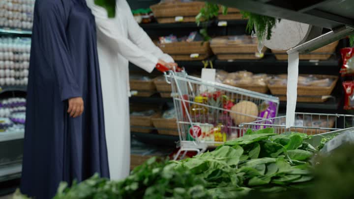 المحاصيل الزراعية الاماراتيه ذات الجودة العالية، انتقاء أجود أنواع الخضراوات الطازجة، امرأه عربيه خليجيه اماراتيه ترتدي عباءه رماديه تقوم ب انتقاء الخضار الطازج برفقه عائلتها، قسم الخضراوات في السوبر ماركت، توفيرالمنتجات للمستهلك ، محاصيل محليه