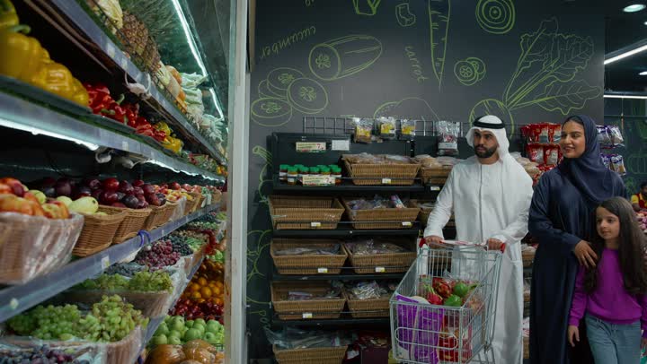 الإعجاب بجودة الفواكه والخضراوات، منتجات محلية وطنية، رجل عربي خليجي اماراتي برفقة عائلته يقوم بانتقاء فاكهة الاناناس في السوبرماركت، مشاركة الأسرة في توفير وشراء اللوازم والإحتياجات المنزلية، محاصيل زراعية اماراتيه