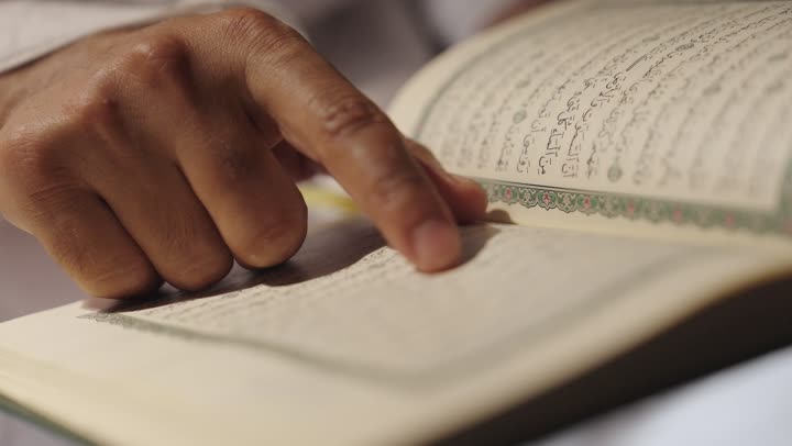 تلاوة كتاب الله،  قراءة القرآن الكريم بتمعن وتركيز, التقرب الى الله بالعبادة والطاعة, أداء مناسك الحج والعمرة، تصوير لرجل عربي سعودي خليجي يرتدي ملابس الإحرام ويمسك بين يديه المصحف الشريف