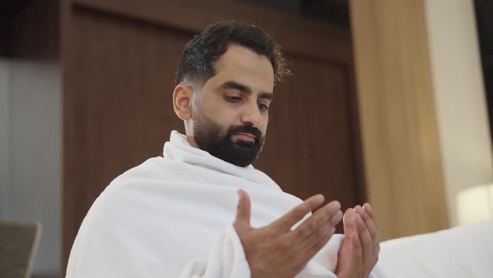 التقرب الى الله بالصلاة والعبادة، أداء العمرة في مكة المكرمة ، مفهوم العبادة والتقرب الى الله، تصوير لرجل مسلم عربي سعودي خليجي يرتدي ملابس الاحرام يرفع يديه للأعلى بإيماءات الدعاء، أداء مناسك الحج والعمرة .