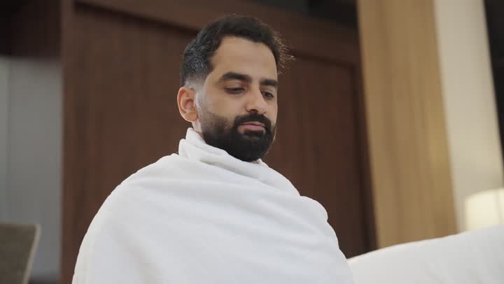 أداء العمرة في مكة المكرمة ، التقرب الى الله بالصلاة والعبادة، مفهوم العبادة والتقرب الى الله، تصوير لرجل مسلم عربي سعودي خليجي يرتدي ملابس الاحرام يرفع يديه للأعلى بإيماءات الدعاء، أداء مناسك الحج والعمرة .
