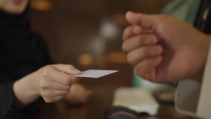 استخدام الوسائل والتقنيات الحديثة في الدفع الالكتروني, خدمة العملاء في الفنادق السياحية,الاستعلام والاستفسار عن الخدمات الفندقية ، اجراءات الحجز والدخول في مكتب الاستقبال, استلام بطاقه الغرفه ، سيده عربيه خليجيه سعوديه ترتدي العباءه والحجاب تعمل في مجال الاستعلامات