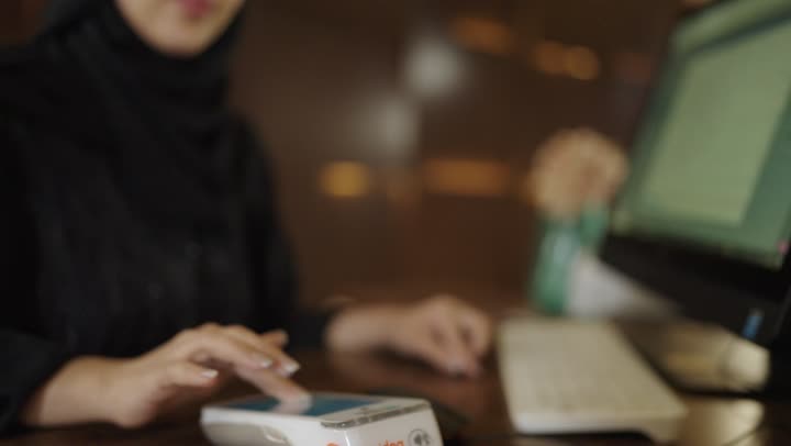 خدمة العملاء في الفنادق السياحية,الاستعلام والاستفسار عن الخدمات الفندقية ، اجراءات الحجز والدخول في مكتب الاستقبال, استلام بطاقه الغرفه ، الدفع الالكتروني عبر بطاقة الصراف, سيده عربيه خليجيه سعوديه ترتدي العباءه والحجاب تعمل في مجال الاستعلامات