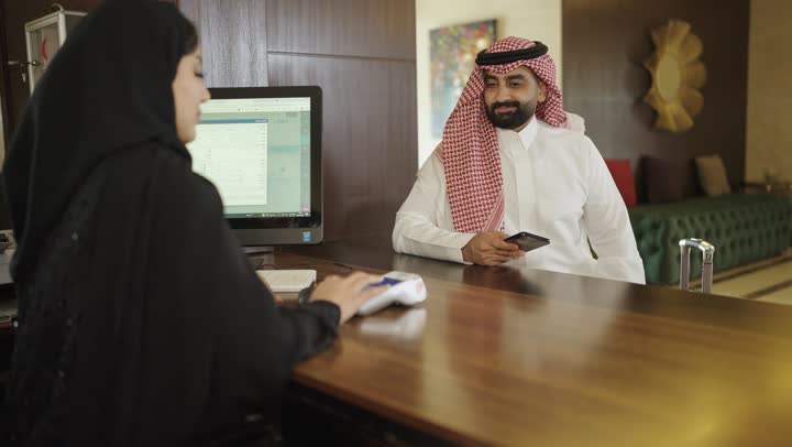 Customer service in tourist hotels, reservation and check-in procedures at the reception desk, a Saudi Arabian Gulf woman wearing an abaya and hijab working in the field of information, inquiries and inquiries about hotel services