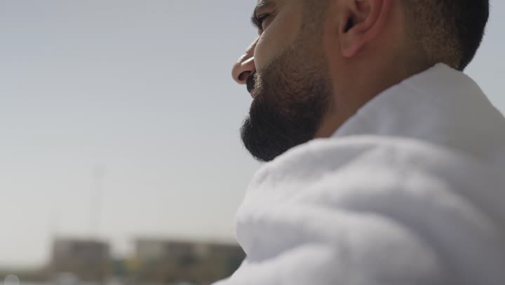 The concept of the pillars of Islam, performing religious duties, performing Hajj and Umrah rituals, performing Umrah in Mecca during the holy month of Ramadan, the arrival of pilgrims from within Saudi Arabia, a Saudi Arab pilgrim wearing Ihram clothes holding a prayer bead in his hand