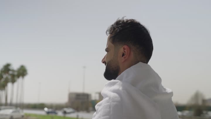 حاج عربي سعودي يرتدي ملابس الإحرام يمسك بيده السبحه ، مفهوم أركان الإسلام , أداء الفرائض الدينية، أداء مناسك الحج والعمره ، أداء العمرة في مكة المكرمة في شهر رمضان المبارك، قدوم الحجاج من داخل السعودية
