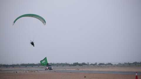 رجل يقوم بانزال مظلي في الصحراء، رفع علم المملكة العربية السعودية، راية التوحيد والإسلام وشعار الهوية الوطنية، مفهوم حب الوطن والانتماء اليه، الاخلاص والولاء للبلاد، الاحتفال بالمناسبات والاعياد الوطنية، ذكرى العيد الوطني 23 سبتمبر، يوم العلم 11 مارس