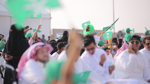 Raising the flags of the Kingdom of Saudi Arabia, the banner of monotheism and Islam and the slogan of national identity, Saudi citizens celebrating on the road, the concept of love of the homeland and belonging to it, loyalty and allegiance to the country, celebrating national occasions and holidays, the anniversary of the National Day on September 23, Flag Day on March 11