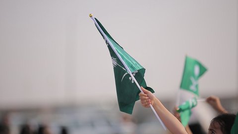 Raising the flags of the Kingdom of Saudi Arabia, the banner of monotheism and Islam and the slogan of national identity, Saudi citizens celebrating on the road, the concept of love of the homeland and belonging to it, loyalty and allegiance to the country, celebrating national occasions and holidays, the anniversary of the National Day on September 23, Flag Day on March 11