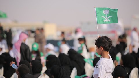 Raising the flags of the Kingdom of Saudi Arabia, the banner of monotheism and Islam and the slogan of national identity, Saudi citizens celebrating on the road, the concept of love of the homeland and belonging to it, loyalty and allegiance to the country, celebrating national occasions and holidays, the anniversary of the National Day on September 23, Flag Day on March 11