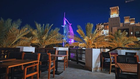 فندق برج العرب المضيء في الليل في مدينة دبي، النمو والتطور العمراني على ساحل الخليج العربي، جذب واستقطاب السياح من انحاء العالم، اطلالة احدى المطاعم على الفن الهندسي المعماري للأبراج وناطحات السحاب، الوجهة السياحية في الامارات العربية المتحدة