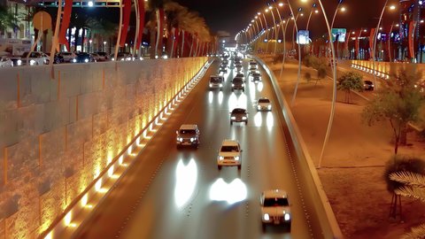 حركة وسائل النقل والمواصلات في الليل، تصوير درون جوي لطريق الملك فهد في عاصمة المملكة العربية السعودية، نمو وتطور البنية التحتية في مدينة الرياض، الفن الهندسي المعماري للأبراج والمباني السكنية والتجارية
