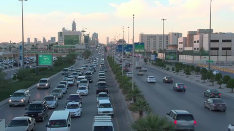 Daytime traffic, aerial drone footage of King Fahd Road in the capital of Saudi Arabia, the growth and development of infrastructure in Riyadh, and the architectural art of towers, residential and commercial buildings.